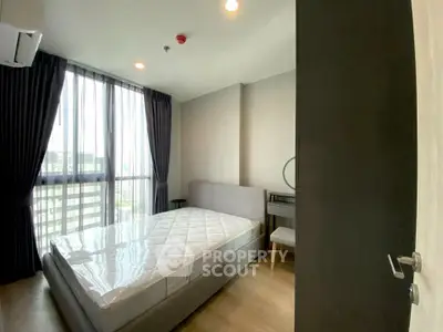 Modern bedroom with large window and stylish furnishings in a high-rise apartment.