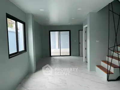 Spacious modern interior with sleek staircase and large windows, perfect for natural light lovers.