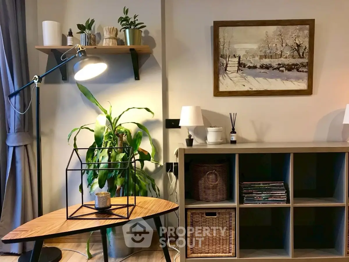 Cozy living room with stylish decor, featuring a wooden table, indoor plants, and a scenic wall painting.