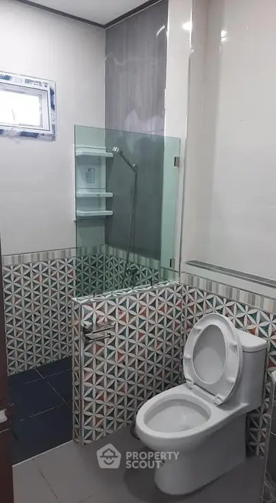 Modern bathroom with geometric tile design and glass shower enclosure