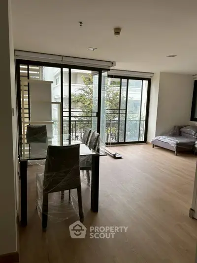 Modern living room with large windows and dining area, featuring a cozy sofa and elegant dining set.