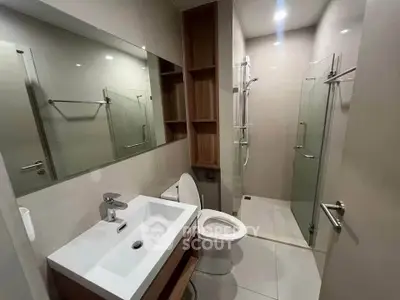 Modern bathroom with glass shower and sleek vanity in contemporary apartment.