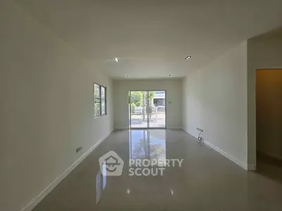 Spacious unfurnished living room with large windows and glossy tiled floor, offering abundant natural light.