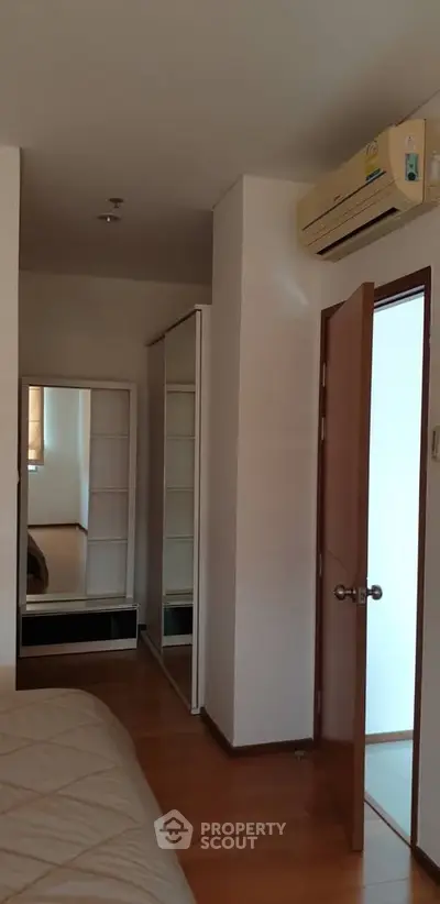 Spacious bedroom with wooden flooring and built-in wardrobe, featuring air conditioning for comfort.