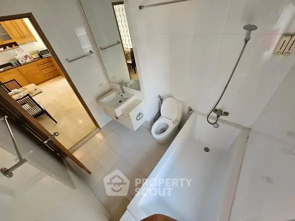 Modern bathroom with bathtub and view into kitchen area