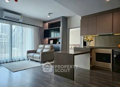 Modern open-layout living room with sleek kitchen and large windows in a stylish apartment.