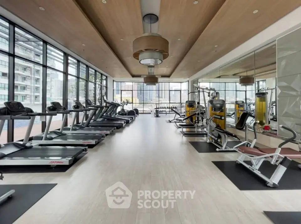 Spacious modern gym with state-of-the-art equipment and city views, perfect for fitness enthusiasts.