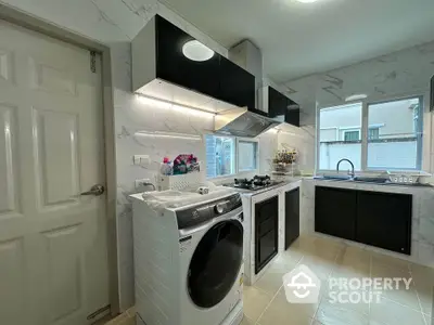 Modern kitchen with washing machine and sleek black cabinets