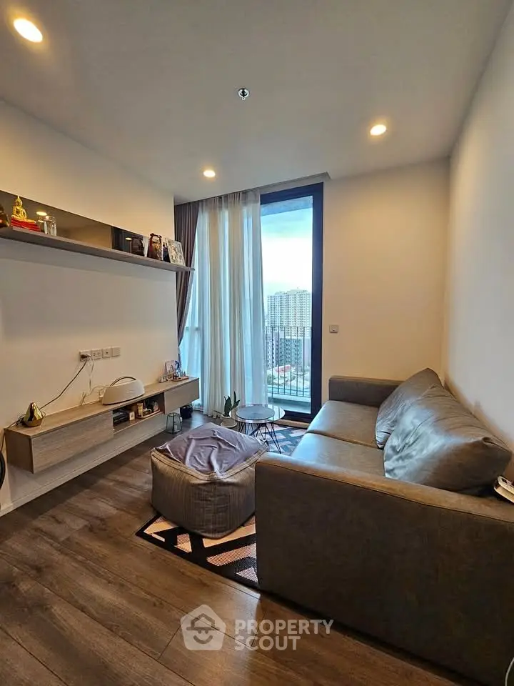 Modern living room with cozy sofa and large window offering city view, perfect for relaxation and entertaining.