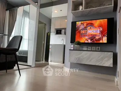 Modern living room with sleek TV setup and view into compact kitchen area.