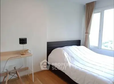 Cozy bedroom with natural light and modern furnishings in a stylish apartment.