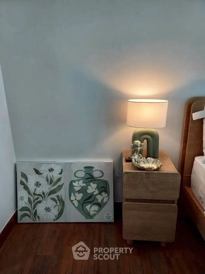 Stylish bedroom corner with modern lamp and artistic decor on wooden nightstand.