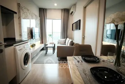 Charming modern studio apartment with integrated living space, featuring a cozy sitting area, dining setup, and a fully equipped kitchen with a washing machine.