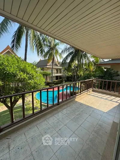 Spacious balcony with pool view in tropical setting, perfect for relaxation and outdoor enjoyment.