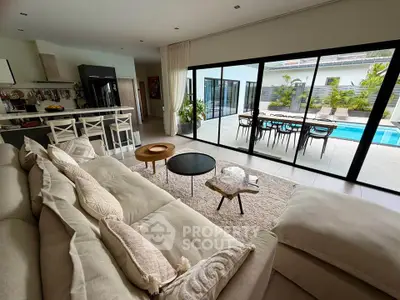 Luxurious open-plan living room with pool view, modern kitchen, and elegant decor.