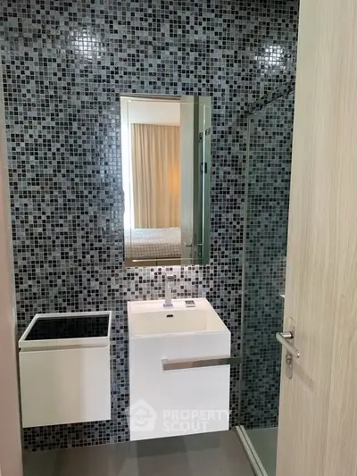 Modern bathroom with mosaic tiles and sleek fixtures in a stylish apartment.