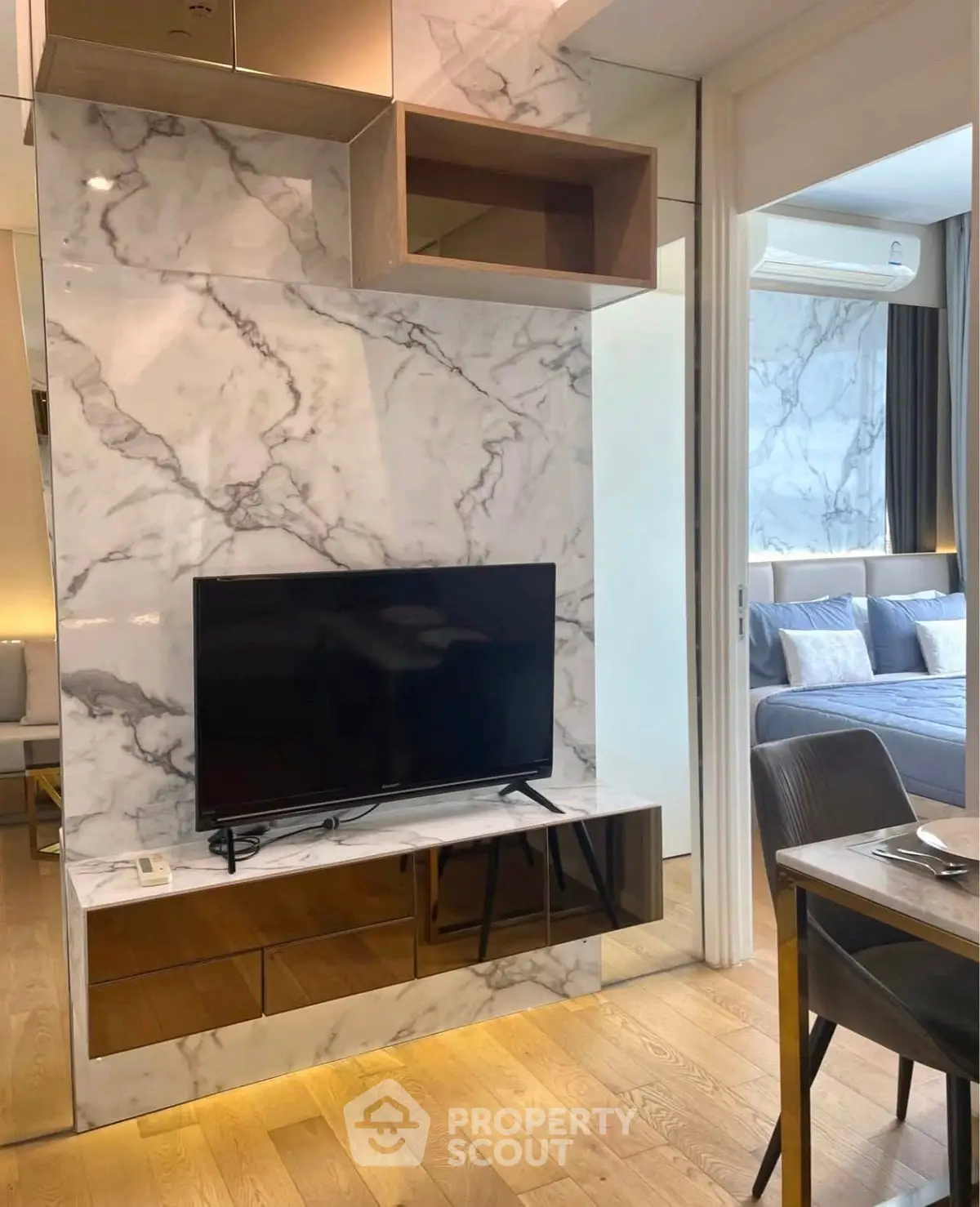 Modern living room with marble accent wall and sleek TV setup, adjacent to a cozy bedroom.
