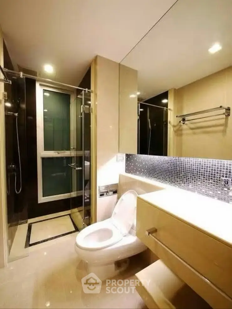 Modern bathroom with sleek fixtures and glass shower enclosure in luxury apartment.