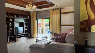 Elegant living room with chandelier and cozy sofa, featuring a large window with a balcony view.