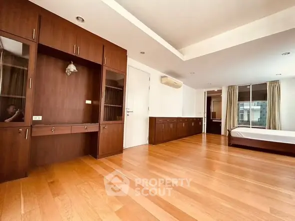 Spacious bedroom with wooden flooring and built-in cabinets in modern apartment.