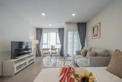 Modern living room with cozy sofa, TV, and dining area in bright apartment