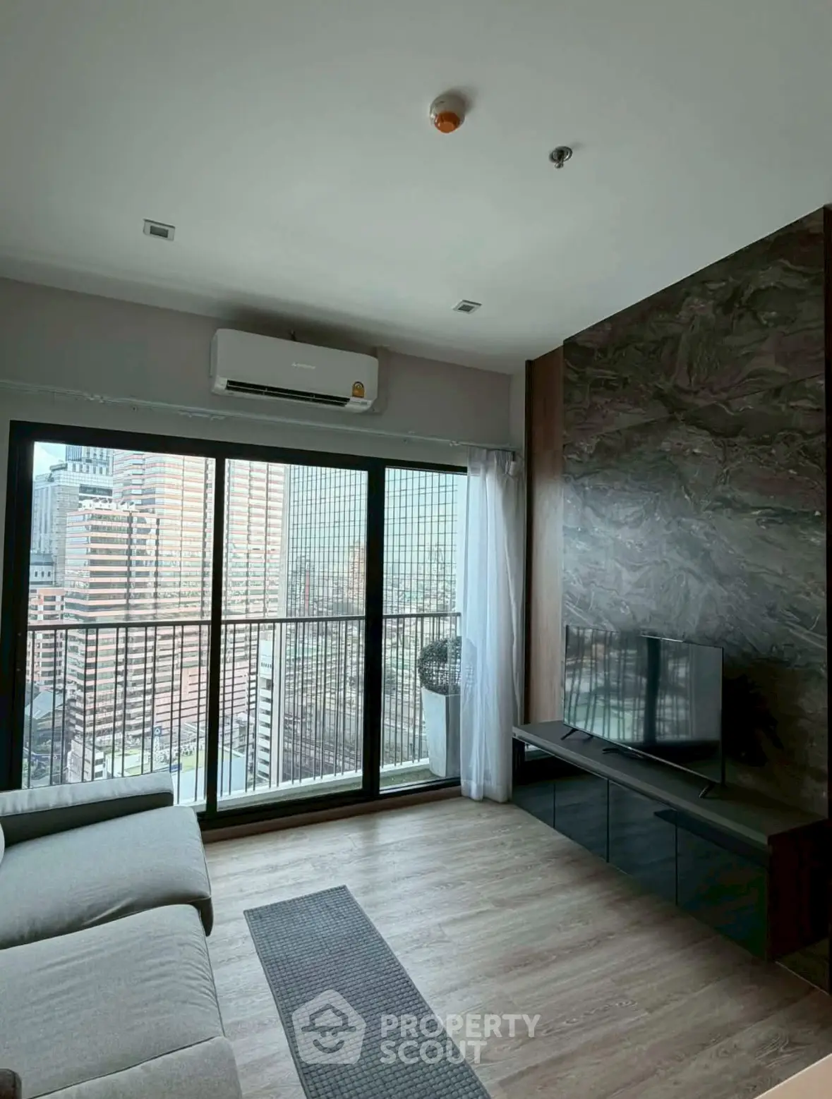 Modern living room with city view, sleek furniture, and large windows.