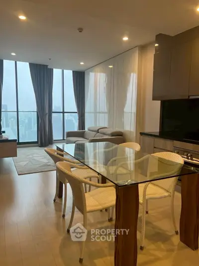Modern high-rise apartment with open living and dining area, featuring floor-to-ceiling windows and city views.