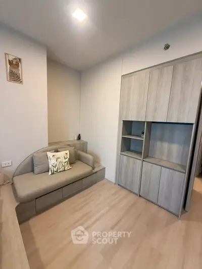 Modern minimalist living room with sleek wooden flooring and stylish built-in storage.