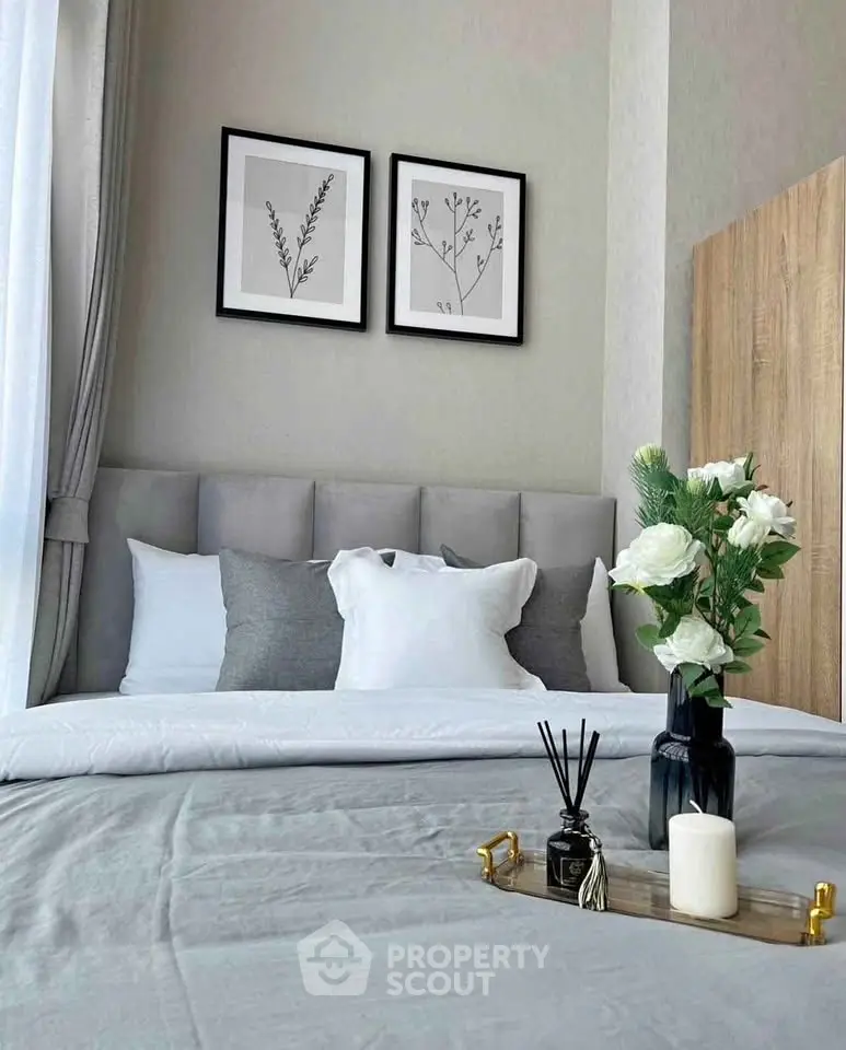 Elegant bedroom with modern decor, featuring a cozy bed, stylish artwork, and fresh flowers for a serene ambiance.