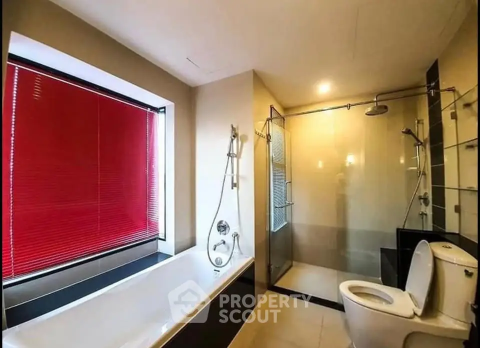 Modern bathroom with bathtub and glass shower enclosure, featuring sleek design and red blinds.