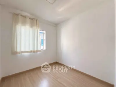 Bright empty room with wooden flooring and a window with curtains, perfect for customization.