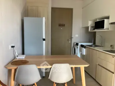 Modern kitchen with dining area, featuring sleek appliances and minimalist design.