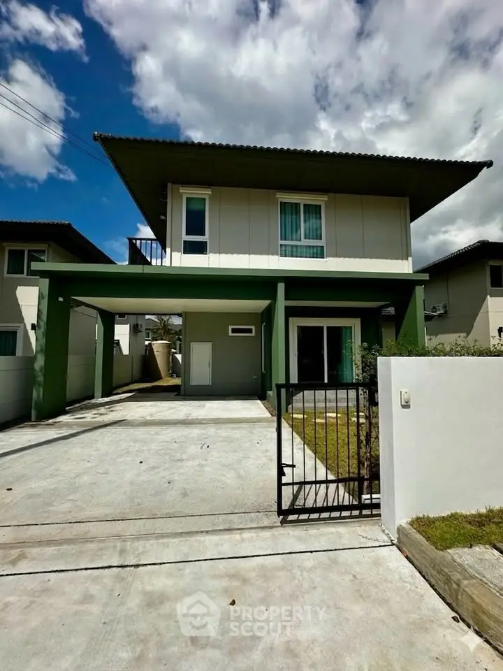 Modern two-story house with green accents and spacious driveway under a clear blue sky.