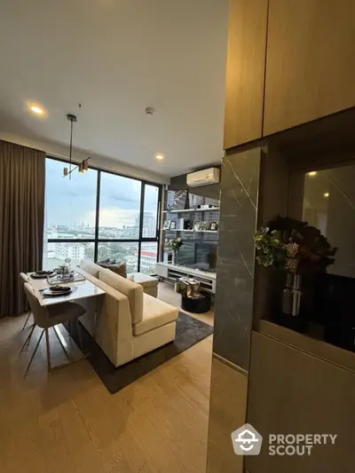 Modern living room with city view, elegant decor, and cozy dining area