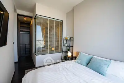 Modern bedroom with large window and stylish decor in a contemporary apartment.
