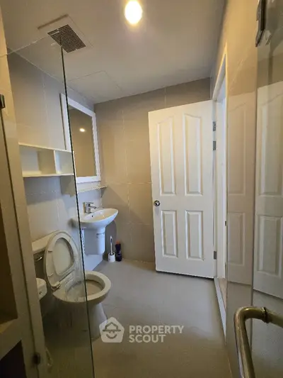 Modern bathroom with sleek design and neutral tones, featuring a glass shower and contemporary fixtures.