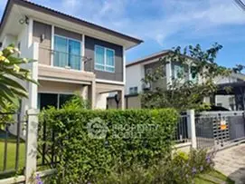 Modern two-story house with lush garden and gated entrance in a serene neighborhood.