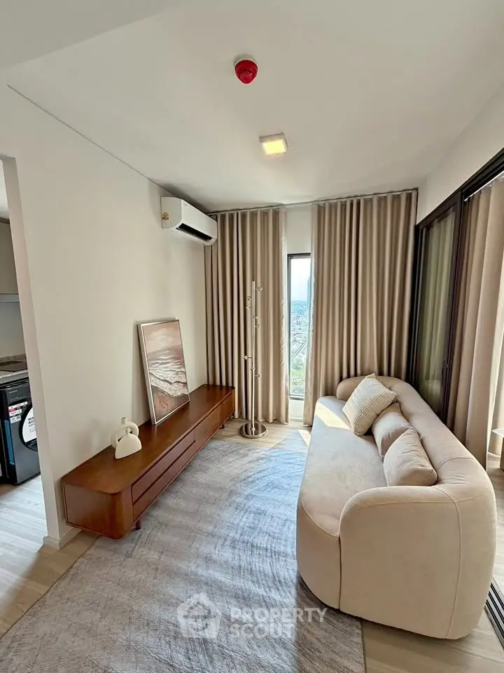 Modern living room with elegant sofa, stylish decor, and large windows offering natural light and scenic views.