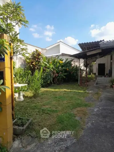 Charming residential garden with lush greenery and outdoor seating area, perfect for relaxation and leisure.