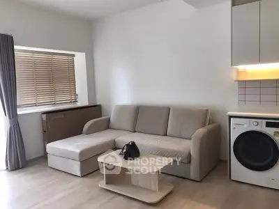 Modern living room with cozy sofa and integrated washing machine in open layout.