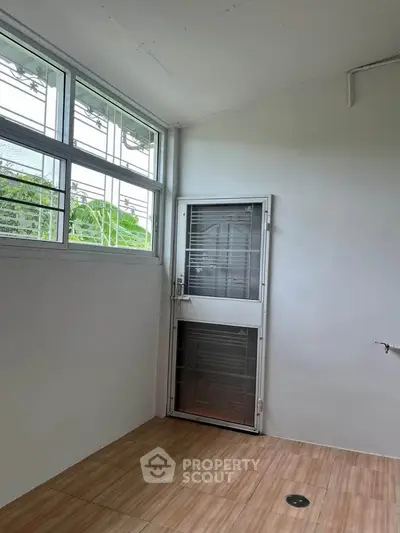 Bright room with large windows and secure door, ideal for storage or utility use.