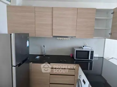 Modern kitchen with sleek cabinets, stainless steel fridge, microwave, and washing machine.