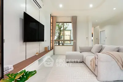 Modern living room with cozy sofa and large TV, bright and inviting space.
