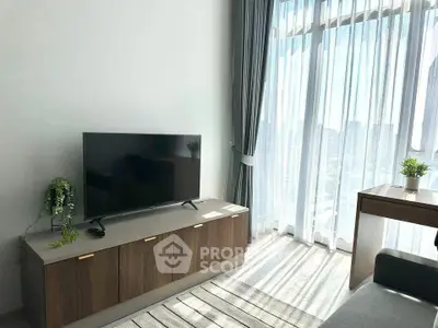 Bright living room with large window, modern TV stand, and cozy decor in a stylish apartment.
