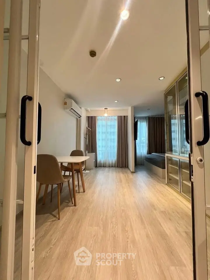 Modern living room with wooden flooring and large windows in a stylish apartment.