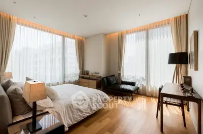 Luxurious bedroom with elegant decor and large windows offering ample natural light.