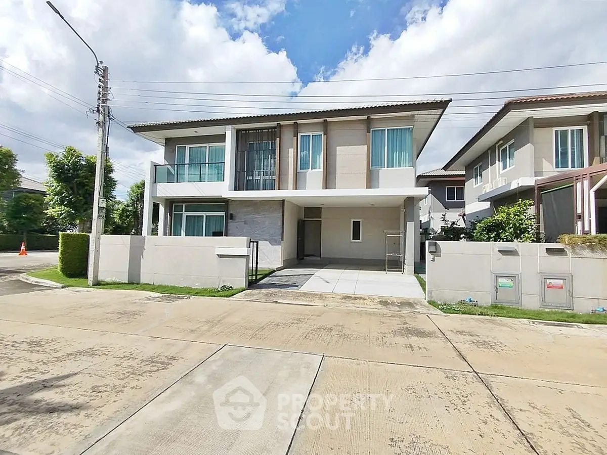 Modern two-story house with large windows and a spacious driveway in a suburban neighborhood.