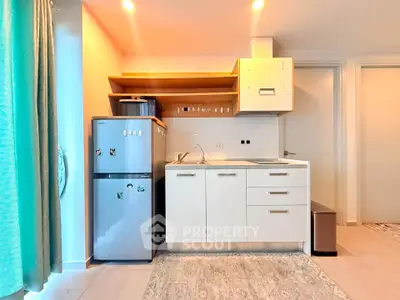 Modern compact kitchen with sleek white cabinets and stainless steel fridge