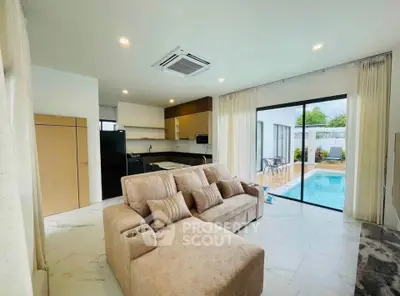 Modern living room with pool view, featuring cozy sofa and sleek kitchen design.