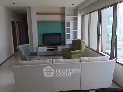 Spacious living room with modern furniture and large windows offering city views.